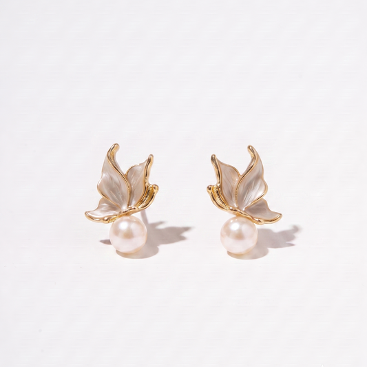 A pair of gold butterfly stud earrings with iridescent white mother-of-pearl wings and a single pearl hanging below each butterfly, photographed on a clean white background.