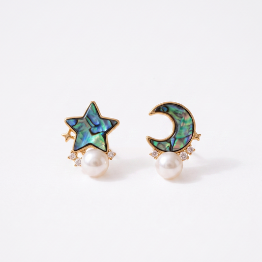 A pair of gold-toned stud earrings featuring an iridescent abalone shell star and crescent moon design, each hanging from a white pearl, set against a clean white background.